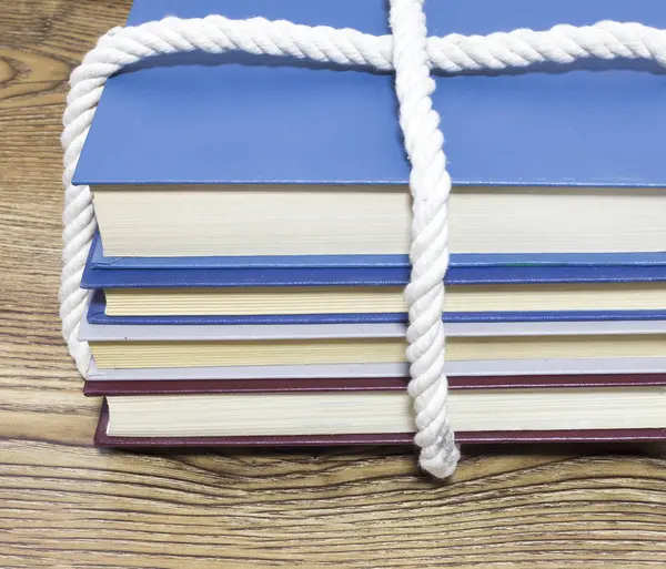 Ahşap masa üzerinde bağlı kitap yığını.