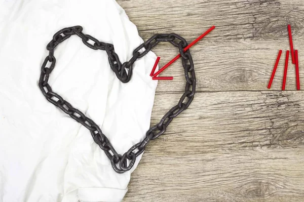 Chain heart shape with red wooden arrow on white rag. — Stock Photo, Image