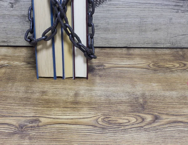 Chain wrapped around books on wooden background. — Stock Photo, Image