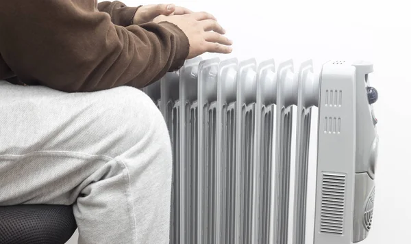 adam beyaz arka plan üzerinde yağ ısıtıcı üzerinde ellerini ısınıyor.