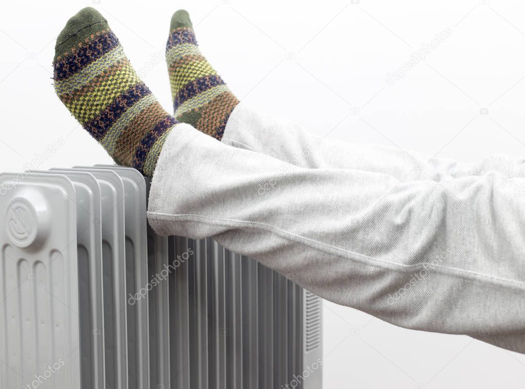 A Man Getting warm in cold winter days. Two feet placed on a heater for warmth.