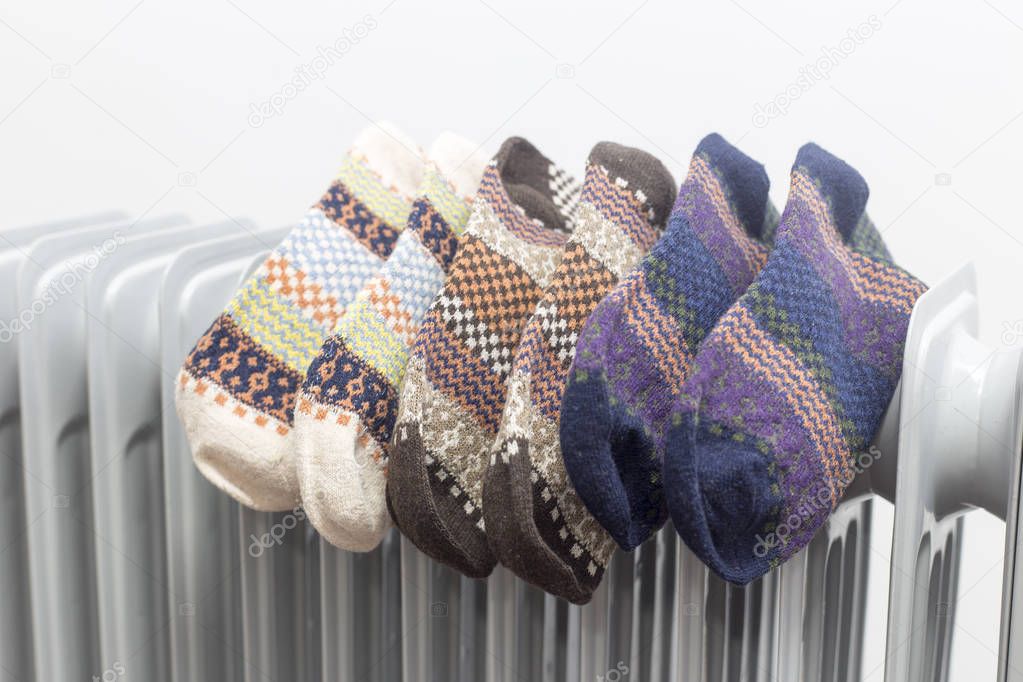 oil heater drying three pair of colourful socks on white background.