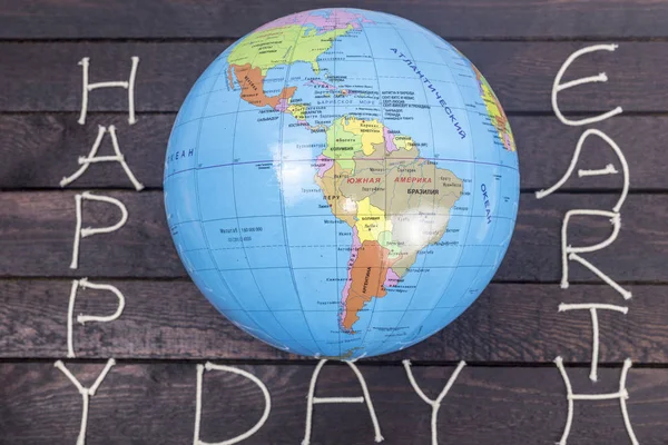 Concept-Earth Day. Globe with the text: Happy Earth Day lays on wooden background