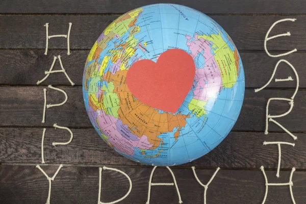 Dag van de aarde concept. Hart papieren kaart legt op wereldbol — Stockfoto
