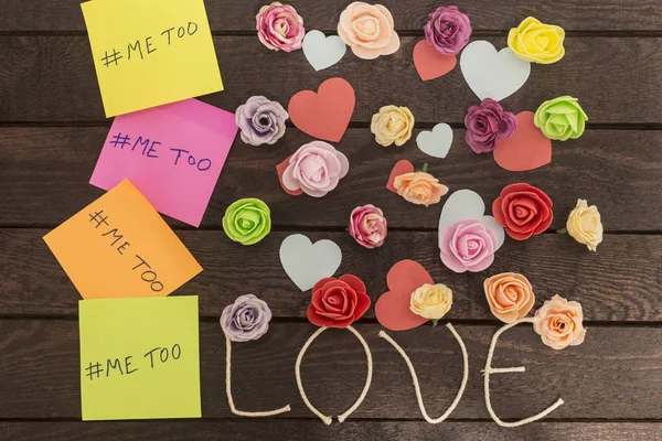 top view of Me too message written in colorful stickers on a love knoted background