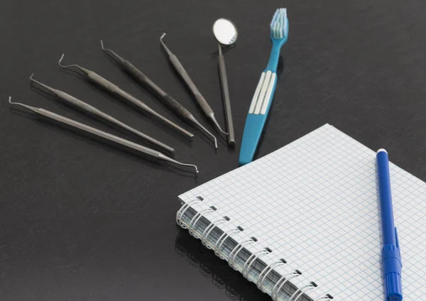 Su uno sfondo grigio è un notebook, strumenti dentali — Foto Stock