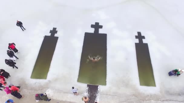 男と女が穴に飛び込む 水を祝福の儀式中にバルク入浴 エピファニーの宗教的な休日 空中展望空気 — ストック動画
