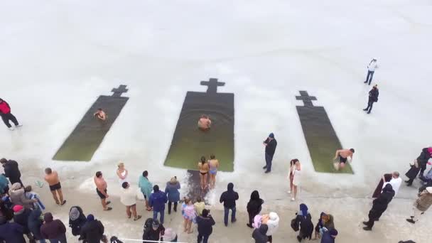 男と女が穴に飛び込む 水を祝福の儀式中にバルク入浴 エピファニーの宗教的な休日 空中展望空気 — ストック動画