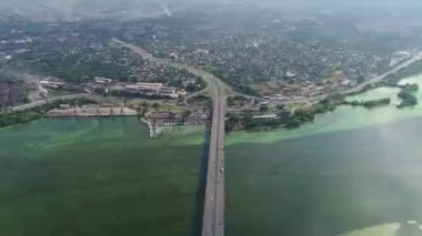 Arabalar nehrin üzerindeki iki köprüye binerler. Kamera aşağı doğru daha yüksek bir yüksekliğe yükselir ve döner. Hava panoramik üst görünümü uçan gökyüzü görüntüsü İHA ile çekim.