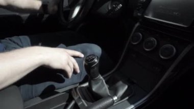Man in warm clothes changing gear during car driving, mechanical speed control at day. Bunch of keys dangling at drive. Inside of car, focus on shift lever of manual transmission and hand. Riding auto
