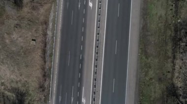 Boş çakıl yolu boyunca güneşli bir sabahta yeşil çayırlar boyunca giden arazi aracının hava görüntüsü. Drone bir arabayı kovalıyor..