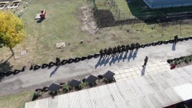 Denizci eğitim subayı üç stajyeri atış poligonunda şınav çekerken izliyor.