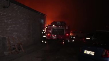 Şehir caddesinde yangın söndürücüyle yangını söndürmeye çalışan ama içerisi tamamen yanmış bir araba yangını.