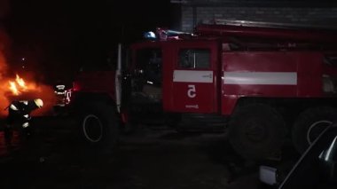 Şehir caddesinde yangın söndürücüyle yangını söndürmeye çalışan ama içerisi tamamen yanmış bir araba yangını.