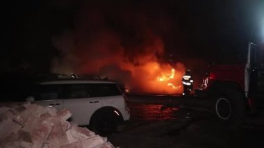 Şehir caddesinde yangın söndürücüyle yangını söndürmeye çalışan ama içerisi tamamen yanmış bir araba yangını.