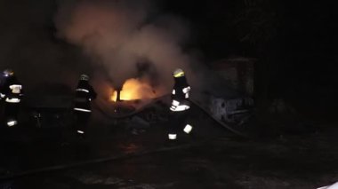 Şehir caddesinde yangın söndürücüyle yangını söndürmeye çalışan ama içerisi tamamen yanmış bir araba yangını.