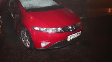 Şehir caddesinde yangın söndürücüyle yangını söndürmeye çalışan ama içerisi tamamen yanmış bir araba yangını.