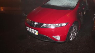 Şehir caddesinde yangın söndürücüyle yangını söndürmeye çalışan ama içerisi tamamen yanmış bir araba yangını.