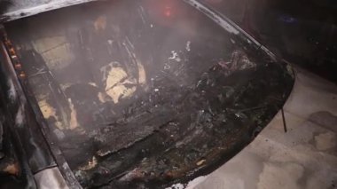 Şehir caddesinde yangın söndürücüyle yangını söndürmeye çalışan ama içerisi tamamen yanmış bir araba yangını.