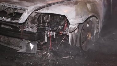 Şehir caddesinde yangın söndürücüyle yangını söndürmeye çalışan ama içerisi tamamen yanmış bir araba yangını.