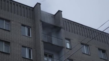 Genel apartman binası, dükkan tentelerinin üzerinde DX gündüz çekim yapan dış cephe. Tuğla cephede pencereden yangın çıkışı