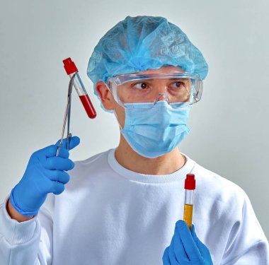 Koronavirüs COVID19, HIV, ebola ya da diğer tehlikeli enfeksiyonlar için kan testi yapan maskeli bir doktor. Doktor portresi, bulanık tıbbi geçmiş, şablon, duvar kağıdı. Coronavirus hastalığı 