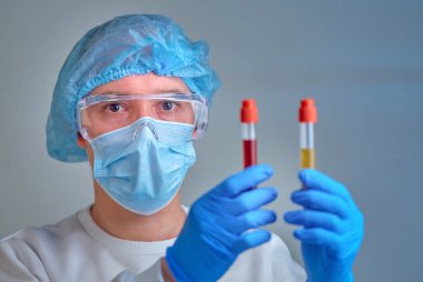 Kan testi tüpü, koronavirüs COVID19, HIV, ebola veya diğer tehlikeli enfeksiyonları tutan maskeli bir doktor. Tıbbi geçmiş, enstrümanlar, şablon, duvar kağıdı. Coronavirus hastalığı konsepti. Doktor portresi