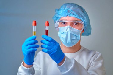 Kan testi tüpü, koronavirüs COVID19, HIV, ebola veya diğer tehlikeli enfeksiyonları tutan maskeli bir doktor. Tıbbi geçmiş, enstrümanlar, şablon, duvar kağıdı. Coronavirus hastalığı konsepti. Doktor portresi