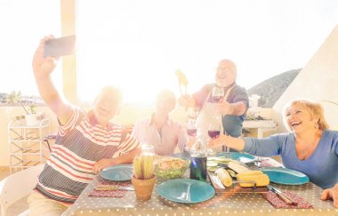 Mutlu bir selfie yeme ve içme eğlenceli bir Barbekü batımında - emekli insanlar olan çatıdaki yaparken kırmızı alarak yaşlılar şarap gülüyor birlikte - neşeli yaşlı mutluluk kavramı