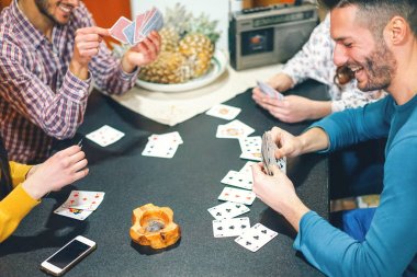 Mutlu arkadaşları oyun kağıtları evde - eğleniyor ve oturma odasında daire - dostluk, oyun, eğlence kavramının poker oynamaya gülüyor Gençler - kartlar üzerinde odaklanmak