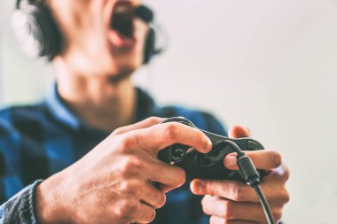 Genç adam eğleniyor video online kullanarak kulaklık ve mikrofon - erkek ellerini tutarak bir joystick oyun yakından - Vintage filtre - insanlar, teknoloji, kavram kumar oyunları oynamak