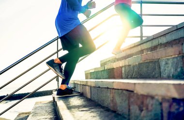 Couple running on stairs at sunset - Friends making a workout session exercising to get on staircase outdoor - Close up legs of people running - Sport, Health, lifestyle people concept clipart