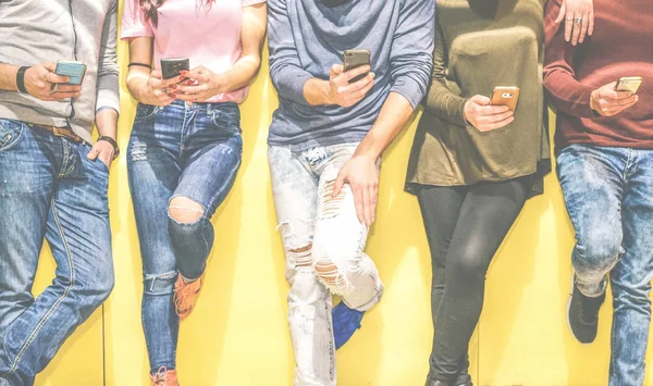 Grup genç arkadaşlar cep telefonları - çok ırklı insanlar akıllı telefon ile sosyal ağ bağlanma - genç nesil için yeni teknoloji kavram bağımlısı kullanarak bir duvara yaslanmış