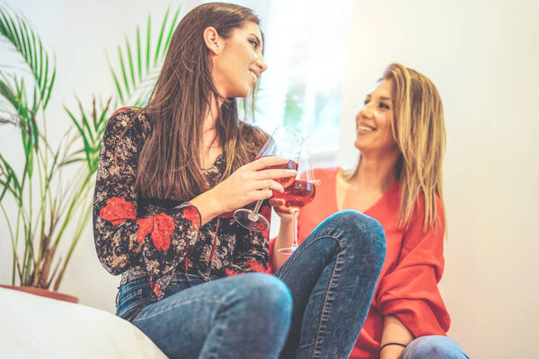 Молодые женщины тосты бокалы розового вина в их доме - Счастливые друзья наслаждаются время вместе пить коктейли и получать удовольствие - Концепция людей, напитки, образ жизни - Сосредоточьтесь на левой руке
