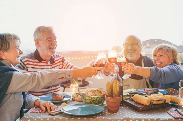 楽しんで満足の年長の友人でバーベキュー テラス屋外 夕食乾杯グラスと笑って一緒に 友情と高齢者のライフ スタイルのコンセプトを作る人々 と成熟の赤ワインと応援 — ストック写真