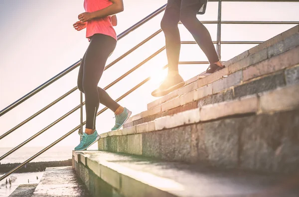 View of runners legs having a workout session on city stairs outdoor - Close up  of people running at sunset - Sport, jogging, health lifestyle  concept -