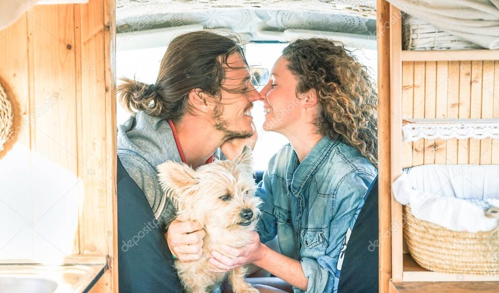 Happy couple close to kiss inside a vintage minivan with their dog during a road trip - Young people having a tender moment in vacation holidays - Travel, love, relationship lifestyle concept