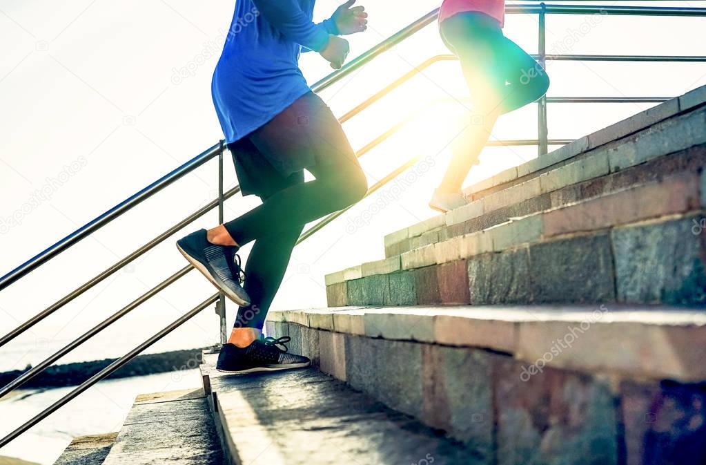 Couple running on stairs at sunset - Friends making a workout session exercising to get on staircase outdoor - Close up legs of people running - Sport, Health, lifestyle people concept