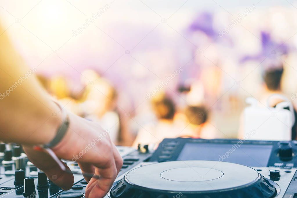 Close up of DJ's hand playing music at turntable on a beach party festival - Portrait of DJ mixer audio in a beach club above the crowd dacing and having fun - Party, summer, music and people concept