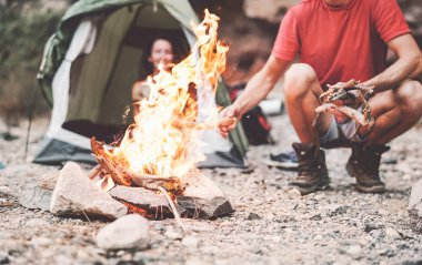 Vahşi ormanda kamp yaparken ateş yakan mutlu çift gençlerin bir sonraki şenlik ateşinde seyahat edip kamp yapması tatil yaşam tarzı konsepti.