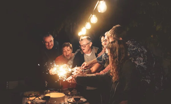 ディナーナイトパーティーの屋外で楽しい家族 外の花火と一緒に祝う混合年齢の人々のグループ 休日の文化と親のライフスタイルの概念 — ストック写真