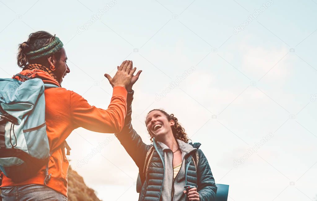 Happy friends stacking hands while doing trekking excursion on mountain - Young tourists walking and exploring the wild nature - Trekker, team, hike and travel people concept