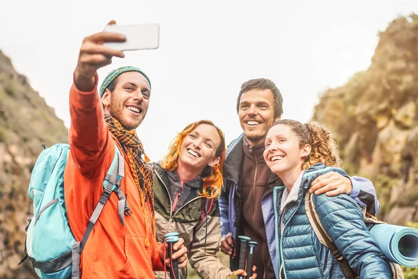 Amigos felices tomando foto selfie con cámara móvil en las montañas - Grupo de jóvenes trekking y divertirse con las nuevas tendencias tecnológicas - Deporte, senderismo, Tecnología y concepto de redes sociales —  Fotos de Stock