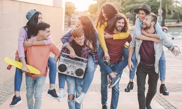 Amigos felices divirtiéndose caminando a cuestas en el centro de la ciudad - Grupo de jóvenes riendo y compartiendo tiempo juntos al aire libre - Cultura juvenil — Foto de Stock