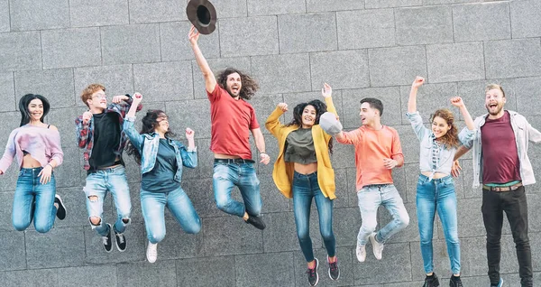 Group of young people jumping together outdoor - Happy millennial friends celebrating success in college - Youth culture lifestyle and friendship concept