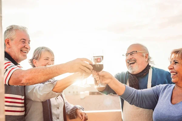 Feliz idosos amigos beber vinho tinto no terraço por do sol - Pensionistas pessoas se divertindo desfrutando de tempo juntos ao ar livre - Idosos conceito de estilo de vida aposentadoria — Fotografia de Stock