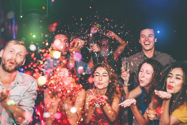 Счастливые друзья, бросающие конфеты в ночном клубе - Группа молодых людей, весело празднующих Новый год вместе в дискоклубе - Молодежная культура развлекательная концепция образа жизни — стоковое фото