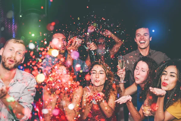 Amigos felizes fazendo festa jogando confete na boate - Jovens do grupo se divertindo celebrando feriados de ano novo juntos no clube de discoteca - Conceito de estilo de vida de entretenimento da cultura juvenil — Fotografia de Stock