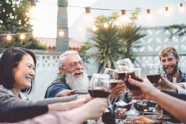 Jantar em família feliz e brindar copos de vinho tinto ao ar livre - Pessoas com diferentes idades e etnia se divertindo no jantar de churrasco - Conceito de atividades de fim de semana de jovens e idosos para pais — Fotografia de Stock