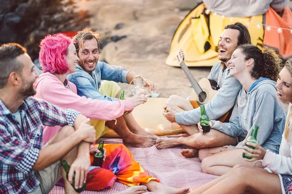 Amigos felices divirtiéndose acampando al aire libre - Jóvenes bebiendo cervezas y tocando la guitarra en el camping junto a la playa - Cultura juvenil y concepto de vacaciones de viaje — Foto de Stock